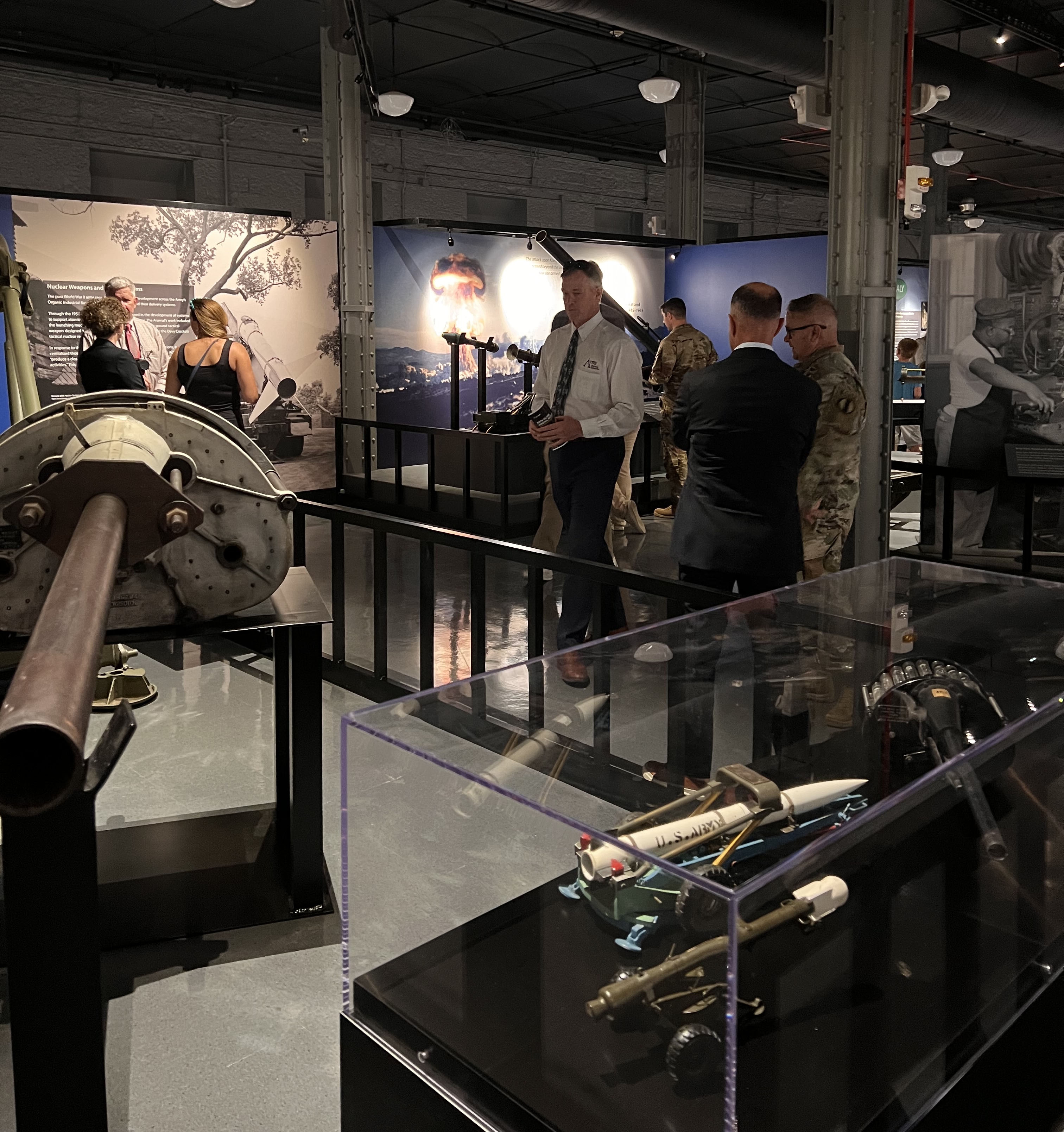 Several people looking at museum exhibits. Some are in Army Uniform and some in casual clothing.